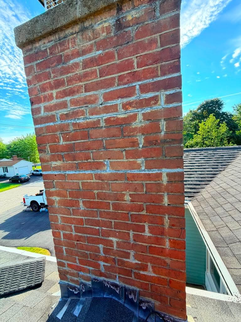 Repointed red brick chimney with fresh mortar joints in Massachusetts