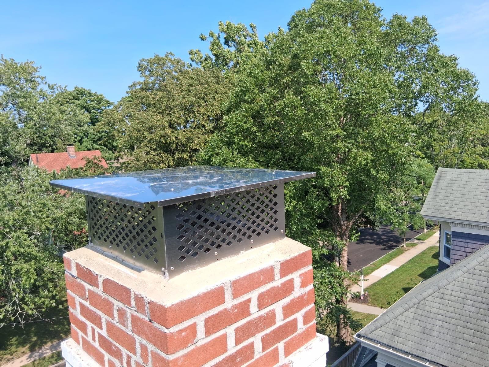 Stainless chimney cap installed on a red brick chimney by Crown Chimney in Greater Boston