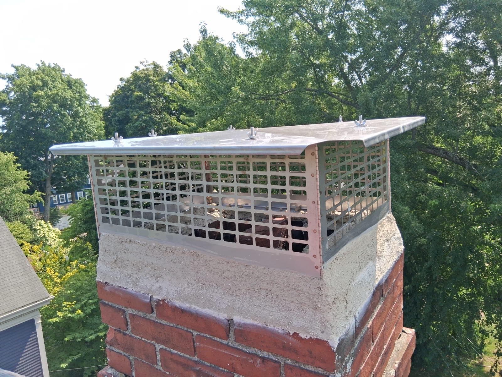 Stainless steel mesh chimney cap installed on a parged chimney in Massachusetts
