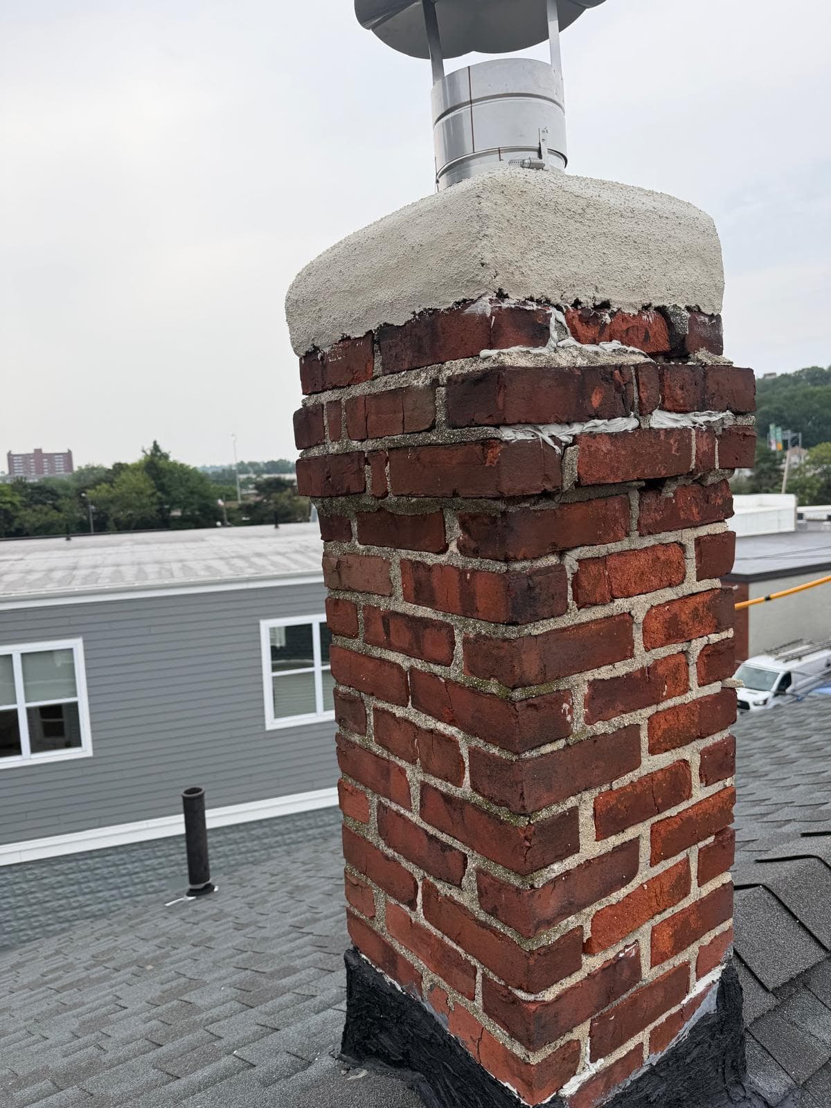 Chimney with a new parged crown, repaired brick, and a stainless rain cap in Massachusetts
